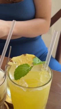 Masada üç farklı içecek. Sağlıklı yiyecek suyu. Ananas suyu. Tuzlu karamel Latte ve buzlu yeşil çay. Spor salonundaki kız kafeteryada cep telefonuyla dinleniyor..