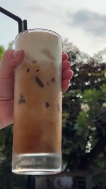Yağmur ormanlarındaki kafede buzlu frappuccino. Yaz tropikal içkisi frappuccino ve dondurma. Yağmur ormanlarında buz küplü sinematik video frappuccino
