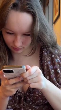 Mısırçiçeği mavisi süveter giyen genç kız akıllı telefon kullanıyor ya da sohbet ediyor, kadın el ele telefonla konuşuyor, evde sabahleyin cep telefonuna mesaj yazıyor. Görüntüyü kapat.