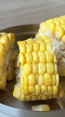 Buharda pişirilmiş mısır koçanlarını bir tabak mısır ve tohumun üzerine koyup yakın plan Şirin Sarı Mısır Taze Kaynatılmış ve Mutfaktaki Yemek Masasında Sıcak. Yüksek kalite 4k görüntü
