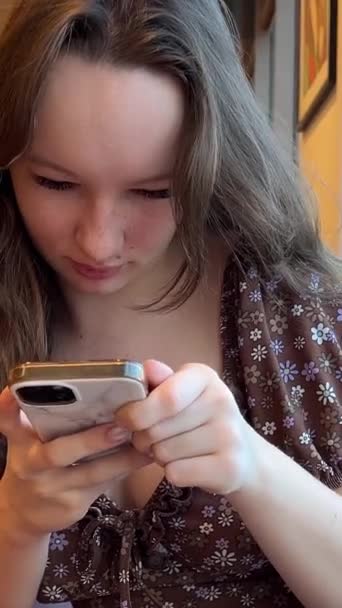 トウモロコシフラワーブルーセーターのティーンエイジャーの学生は スマートフォンやチャットをテキストを使用して 女性の手は 携帯電話を保持し 自宅の朝にリビングルームでモバイル上のメッセージを入力します 閉じる ビュー — ストック動画
