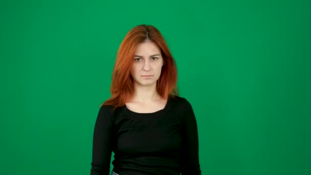 赤毛の少女はカメラの前に手を上げ 指をノーと指差した クロマキースタジオで緑の背景に赤い髪の若い女性の感情をクローズアップヨーロッパのアメリカ人 — ストック動画