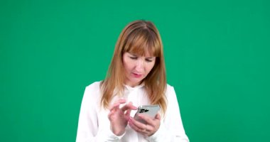 Kız bir numarayı çevirir, parmağını telefon ekranında gezdirir, alışveriş yapar, yeşil arka plandaki açık tenli, Avrupalı Amerikalı genç kadına bakar. Kanada