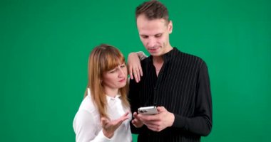 Elinde tablet telefonu olan erkek ve kadın ellerinde yeşil arka planda konuşan kahkahalar toplantıda internet flörtleşen ilişkiler üzerine çalışmayı öğreniyorlar. Çift çözme sorunu