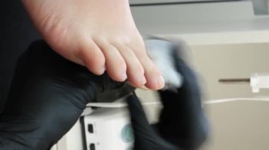 Manikür ve pedikür yapan kadın pedikür yapmadan önce manikür makinesiyle müşterilerinin tırnaklarındaki jöle kabuk cilasını temizler. Güzellik uzmanı eski verniği manikür makinesiyle çıkarıyor. Jölenin çıkarılması. 