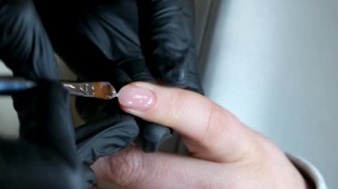 Manikür ve pedikür yapan kadın pedikür yapmadan önce manikür makinesiyle müşterilerinin tırnaklarındaki jöle kabuk cilasını temizler. Güzellik uzmanı eski verniği manikür makinesiyle çıkarıyor. Jölenin çıkarılması. 