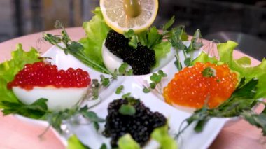 Süslemek için limonlu tekneler yapmak için siyah havyar maydanoz yapraklarıyla süslenmiş bir kasede kaynamış yumurta. Yüksek kalite 4k görüntü