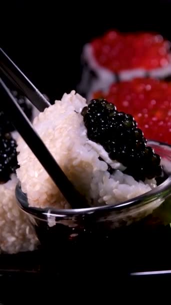 特写乌拉麦寿司卷与红色鱼子酱 金枪鱼 黄瓜和鳄梨分离的黑色背景 美味的日本传统食品 寿司卷 红色和黑色鱼子酱 — 图库视频影像