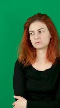 Siyah elbiseli kızıl saçlı bir kız yana bakıyor, gözleri eğik ve çerçevenin içine bakıyor. Duygular, yeşil arka planda genç bir kadını krom anahtar stüdyo duygularında yakından tecrübe eder. 