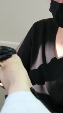Profesyonel ayak masajı, pedikür salonunda ayak bakımı yapan siyah eldivenli kadın doktor ve maske, dairesel yoğurma hareketleriyle masaj yapıyor ayak tedavisi sorunları. Dikey videolar 