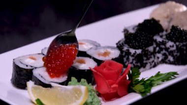 Kırmızı siyah havyarlı suşi tabakta servis ediliyor, küçük bir kaşıkla yakın plan, çok para, zenginlik. Kuralları olmayan lüks bir tatil hayatı, zenginler için yemek, çok para..