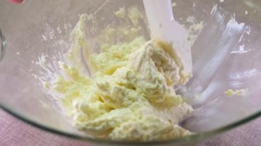 Bir kadın, un serpiştirilmiş ahşap bir masada büyük metal bir kaşıkla kaymak kütlesiyle hamuru karıştırır. Ev yapımı kekler hazırlıyorum. Yüksek kalite 4k görüntü