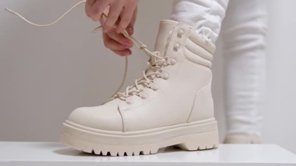 在一个白色背景的经典时装表演中 女人穿米黄色的高鞋带休闲鞋来购买冬季和秋季的乳白色鞋子 高质量的4K镜头 — 图库视频影像
