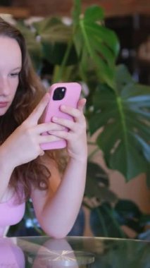 Gadget bağımlılığı. Genç ve çekici bir kadın akıllı telefon kullanır ve kaşlarını çatar ve daireye hoşnutsuzca bakar. Yüksek kalite 4k görüntü