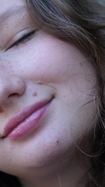 Yüzünde bir gülümseme olan kızıl saçlı kızın görüntüsü. Rüzgarda saçları düzleştirir. Kolunda bir dövme var. Yakın plan. Yüksek kalite 4k görüntü