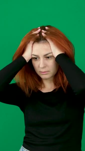 赤毛の女の子は彼女の頭にひどい悪夢を置きました 私が悪いニュースをしたこと 垂直ビデオ クロマキースタジオで緑の背景に赤い髪の若い女性の感情をクローズアップ — ストック動画