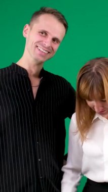 Siyah beyaz elbiseli bir adam ve bir kız, Yin-Yang, yeşil arka planda konuşuyor ve gülümsüyor. Dikey video. Kameraya ve birbirimize baktık. Yüksek kalite 4k görüntü