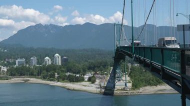 Lions Gate Köprüsü Araba trafiği, Dağlar, Park Yaz Günü Stanley Park demir yapısı güneş parlıyor, Pasifik Okyanusu manzaralı Stanley Park. Ağır çekim, yüksek kalite 4K görüntü