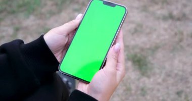 Genç bir kadın yeşil mod ekranlı akıllı telefon kullanıyor. Kız cep telefonu kullanıyor, internette geziniyor, içeriği, videoları, blogları izliyor. Yüksek kalite 4k görüntü