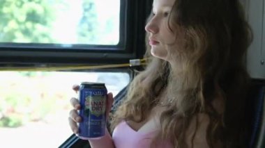 Kanada birası içen bir kız gerçek zencefilli gazoz yüzde yüz doğal aromalı yeşil soda açık havada açık kahverengi masada yeşil arkası ile birlikte, Kanada Vancouver 04.21.2024 