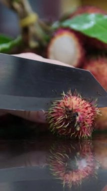 Kadınlar rambutan meyvesini kesmek ve rambutan kabuğunu çıkarmak için bıçak kullanır. Tayland meyvesi. Tatlı ve mevsimlik meyveler. 