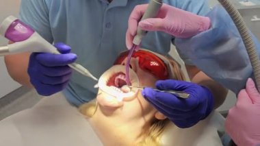 Latest teeth cleaning and whitening technology, nurse and doctor treating patients teeth. Protective masks on the faces of doctors, gloves, cleanliness and sanitation. High quality 8k footage