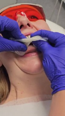 Dişçinin eldiven takıp steril ağız aynası taktığı yakın çekim videosu. Güvenlik gözlüğü takan hasta. Tıbbi muayeneye hazırlanıyorum. Dişçi tedavisi. Dikey video Yüksek kalite 4k