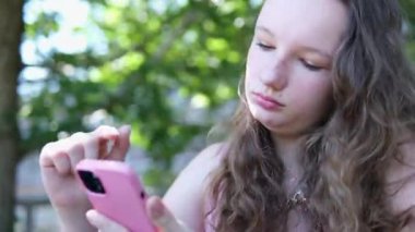 Yakın plan güzel genç kız dans ediyor, müzik dinliyor, pembe bir telefonla çalıyor, numara çeviriyor, internetten alışveriş yapıyor, sosyal ağlarda iletişim kuruyor. Yüksek kalite 4k görüntü