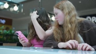 Kız arkadaşlar bir kafede telefonlarındaki fotoğraflara bakıyorlar. Akıllı telefondan bir arkadaşına videoyu gösteriyor, video görüşmesini yapıyor, masada oturuyor. Kadınlar dedikoduyu tartışıyor ve haberleri paylaşıyorlar. Yüksek kalite 4k görüntü