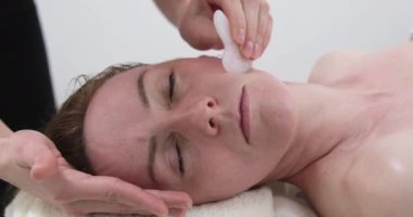 Yüz masajı için gua sha kazıyıcı ile yüz masajı, profesyonel yanak masajı, güzellik salonu, gençlik uzaması, yüz sağlığı. Yüksek kalite 4k görüntü