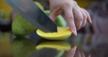 Yeşil mangoyu parçalara ayır. Kadın eli, mangonun nasıl kesildiğini gösterir. Yüksek kaliteli FullHD görüntüler
