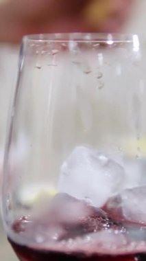 Bir restoranda şarap bardağına kırmızı şarap döküldü. Buzlu şarap, dikey video. Yüksek kaliteli FullHD görüntüler