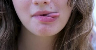 Genç bir kadın dilini yana doğru uzatır ve bir gencin uzun diliyle ileri doğru ilerler. Kız kameraya şakacı bir şekilde yüzünü buruşturur ve dilini dışarı çıkarır.. 