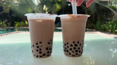 Buzlu ve Tapioca toplu iki Bubble Tea içeceği, büyük bir pipet, muhallebi incili muhallebi köpüğü çayı, gri arkaplan. Yüksek kalite 4k görüntü