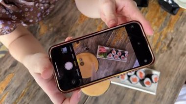 Bir kız yemek bloğunu yönetmek için cep telefonuyla suşi ve mango suyu çekiyor, bir blogcu bir restoranda çalışıyor ve yemek yiyor, yemeklerini filme alıyor ve fotoğraf çekiyor. Yemek fotoğrafları çekiyor.