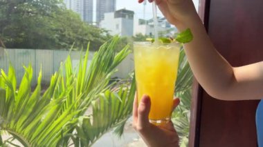 Portakal suyu sportif kızı elinde bir bardak taze sıkılmış meyve suyu ve tropik kır tatili gevşemesi tutuyor. Yüksek kalite 4k görüntü