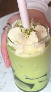 Neşeli bir şekilde gülümseyen bir kadın kazaklı güzel bir kız elinde temiz bir bardakta sıcak bir kibrit çay tutuyor. Yüksek kalite 4k görüntü