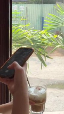 Güzel sarışın kadının sosyal medya için sağlıklı kahvaltısının fotoğraflarını akıllı telefonuyla çekerken yukarı kaldır. O, mutfaktaki masada oturuyor. Yavaş çekim. 