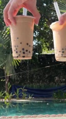 Buzlu ve Tapioca toplu iki Bubble Tea içeceği, büyük bir pipet, muhallebi incili muhallebi köpüğü çayı, gri arkaplan. Yüksek kalite 4k görüntü