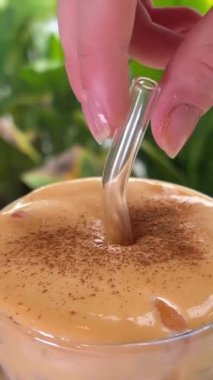 Sarı sıvı. Vietnam 'da bir kafede cam çubukla yumurta kahvesi karıştırmak. Büyük köpüklü lezzetli bir içecek..