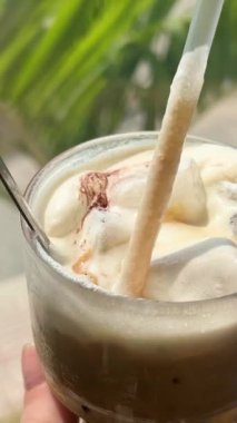 Plastik bardakta soğuk buzlu sütlü kahve ve kafede şeker kamışı pipetleri. Buzlu latte.