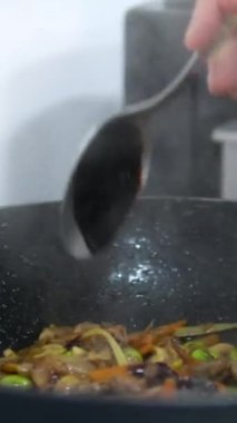 Asya yemeklerine kalın ve koyu sos ekliyorum. Unagi sosu ekle. Teriyaki sosu. Bir adamın eli kaşığı tutar ve bir çorba kaşığı sos ekler. et için