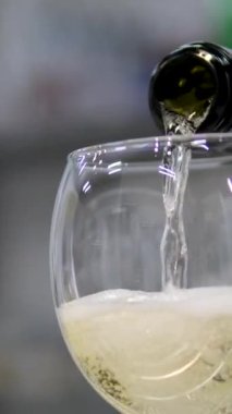 Şampanya dolduruyorum. Bir flüt bardağının karanlık arka planda yavaş çekimde şampanyayla doldurulduğu yakın plan çekimi. Yüksek kalite 4k görüntü