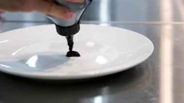 Şef kalbi çikolata dolu torbayla boyar. Şekerlemeci, yemek kursu sırasında çizim yeteneğini gösteriyor. Çikolatalı çiz.