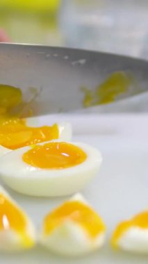 Haşlanmış yumurta kesmek. Dilimlenmiş yumurta dilimleri cam bir yüzeye düşer. Kadın elleri yakın mesafeden haşlanmış yumurtayı kesiyor.. 