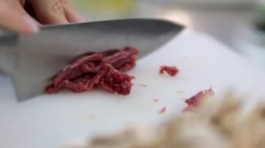 Asya mutfağı aşçılık süreci adım adım. Vermicelli tavası için ince dilimlenmiş et Tayland mutfağı. Tavuğu bıçakla doğrayın. Kesme tahtasında.. 
