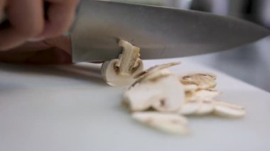 Mutfakta tahta keserken bıçakla şampiyon mantarı doğrayan genç bir kadın. Çiğ organik sebzeler. Diyet sağlıklı yaşam tarzı konsepti. İlginç bir tarif. 4k görüntü