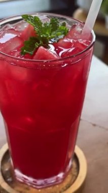 Kızın elinde uzun bardakta plastik pipetler ve karpuz dilimli rüzgar dalgaları var. Karpuz suyu kızı.