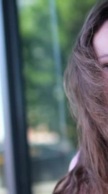 Pembe elbiseli kıvırcık saçlı güzel bir genç kız. Gülümsüyor, omzunun üzerinden bakıyor ve kameradan uzaklaşıyor. Ağır çekim, yüksek kalite 4K görüntü