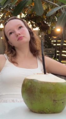 Havuz başında rahatlayan, hindistancevizi içen, lüks tatiller yapan genç bir kadın. Kız kokteyl ile saman kullanıyor. Özel havuz alanı, satılık villa. Elit gayrimenkul alımı. 